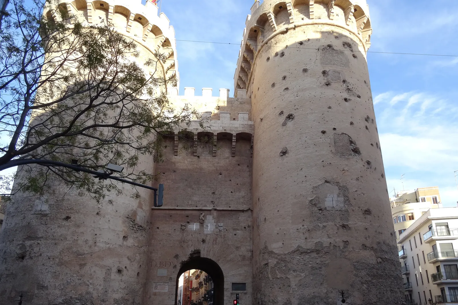 Dvě kulaté věže Torres de Quart ve Valencii, jejich kámen poznamenaný stopami po dělových koulích a kulkách, s obloukem brány mezi nimi